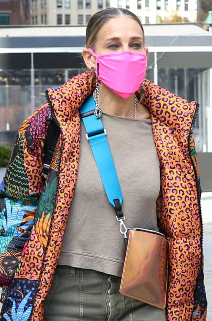 Sarah Jessica Parker pulls her long hair into a ponytail and stays safe with a neon pink face mask