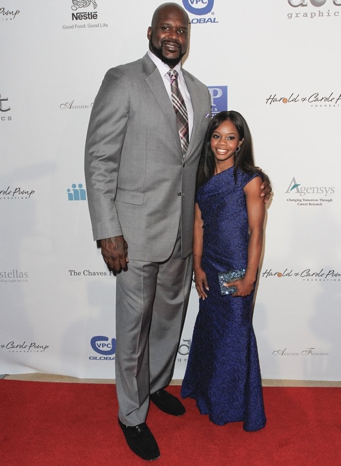 American basketball player Shaquille O'Neal, whose shoes are a size 22, posing with American artistic gymnast Gabby Douglas