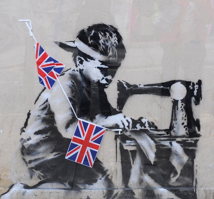 Slave Labour, a mural by British graffiti artist Banksy, depicts a poorly dressed child at a sewing machine assembling a bunting of Union Jack patches