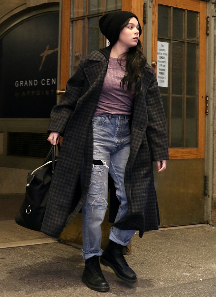 Hailee Steinfeld in a purple ribbed top with ripped jeans and plaid wool coat