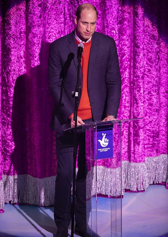 Prince William gives a speech in a red sweater, a white shirt, and a navy blazer