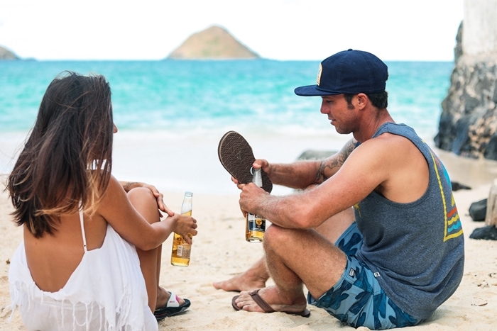 Opening a bottle of Corona beer with a sandal after a surf session at the beach