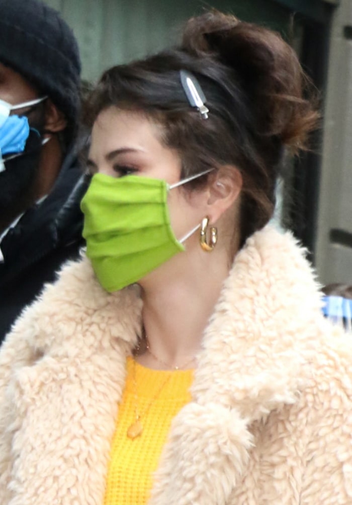 Selena Gomez wears her hair in a messy bun and stays safe with a green face mask