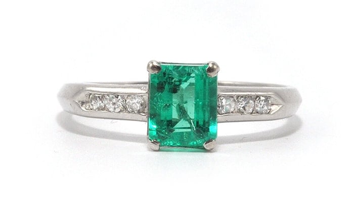 A 0.93-carat bright green Colombian emerald glows between a row of six diamonds set in a platinum band