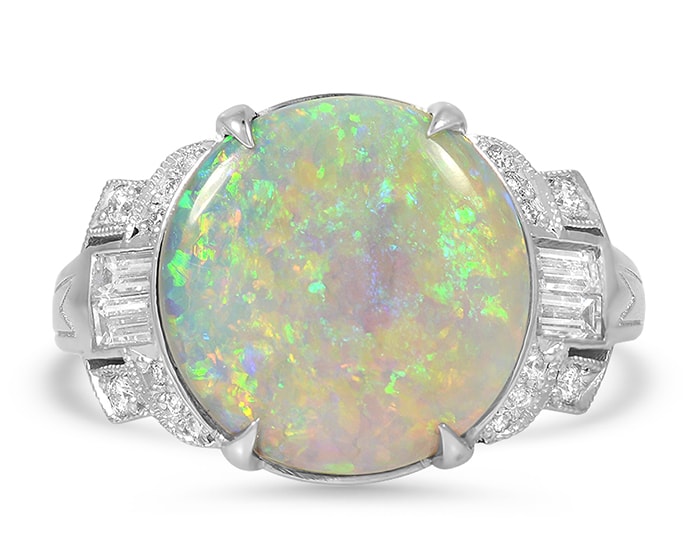 Unique retro-era Felita ring holds a round opal cabochon surrounded by a total of 0.60-carat 20 brilliant and baguette diamonds