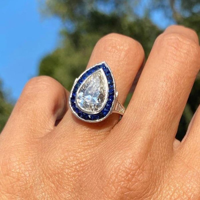 Calibre cut sapphires frame the pear-shaped 5-carat diamond in platinum band