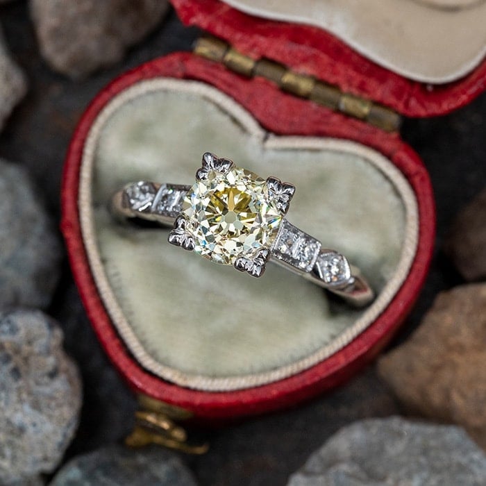 A 1.55-carat fancy yellow old European cut diamond set in a squared fishtail setting with six single cut diamonds on the 14k white gold band