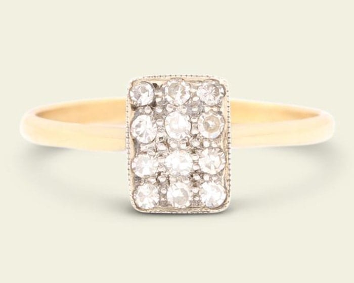 An early Deco engagement ring fashioned in 18k yellow gold band with platinum-topped diamond-studded rectangular face