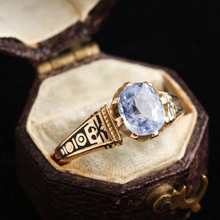 Intricately designed Victorian engagement ring featuring 1.41-carat pale sapphire set in 14k gold band with black enamel detailing
