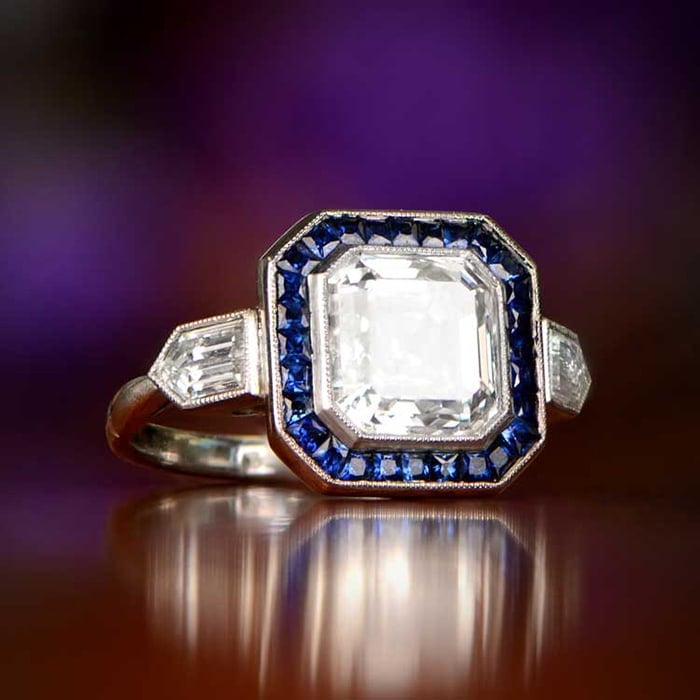 The Crawford ring features a 3.26-carat antique Asscher cut diamond surrounded by French cut Ceylon sapphires with two straight-lined bullet-shaped diamonds on each shoulder