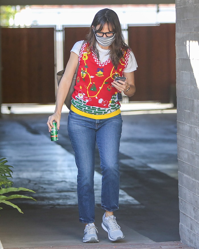 Jennifer Garner embraces festive flair in a playful $17 V28 Christmas sweater vest layered over a white tee, paired with cropped boot-cut jeans and comfy Brooks Ghost 13 sneakers as she leaves her Brentwood office on December 18, 2020
