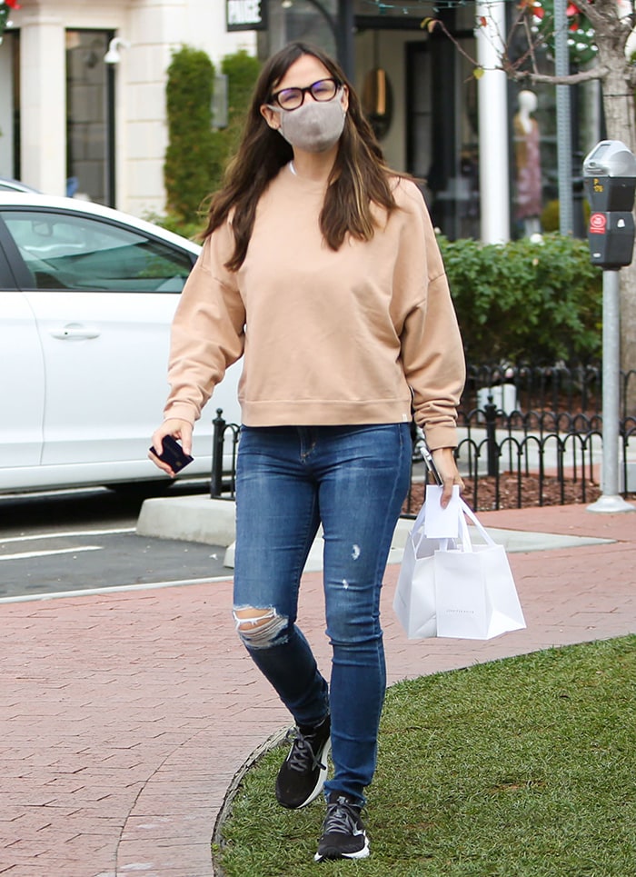 Jennifer Garner wears a beige Tkees sweater with blue ripped jeans