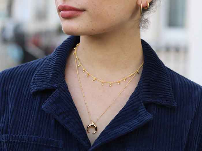 A large horn pendant necklace meets a delicate mini fang necklace done in a chic layered effect