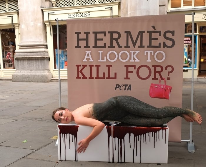 A PETA supporter is body painted to look like a crocodile lying in a pool of blood outside the London Hermes store at The Royal Exchange