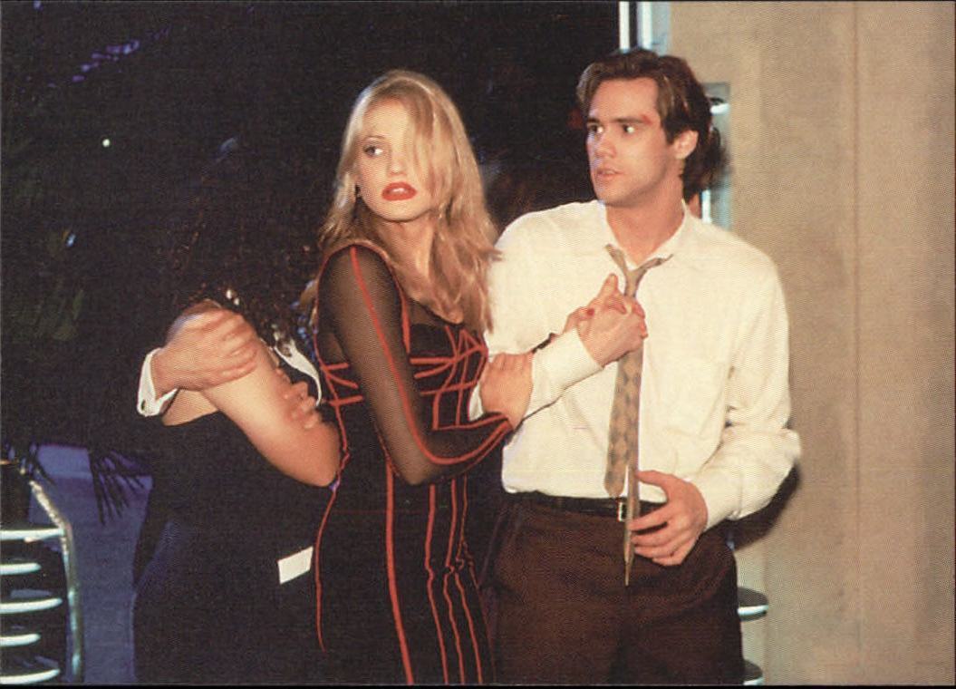 In a tense moment from "The Mask," Cameron Diaz as Tina Carlyle captivates in a form-fitting black dress with bold red geometric lines, designed by Ha Nguyen, while Jim Carrey's Stanley Ipkiss sports a classic white shirt and tie ensemble