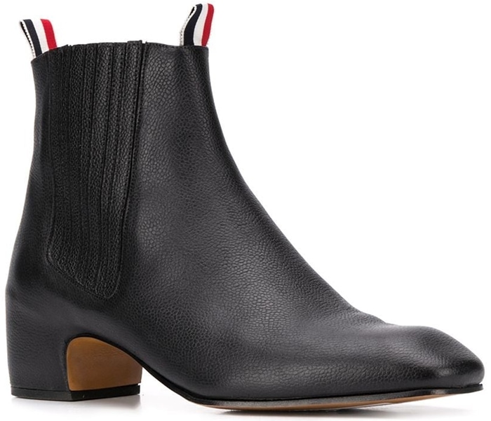 Boasting the iconic three-stripe detailing and a unique block heel, these black calf leather Thom Browne Chelsea boots are distinctive in their design and add a little bit of height to your ensemble