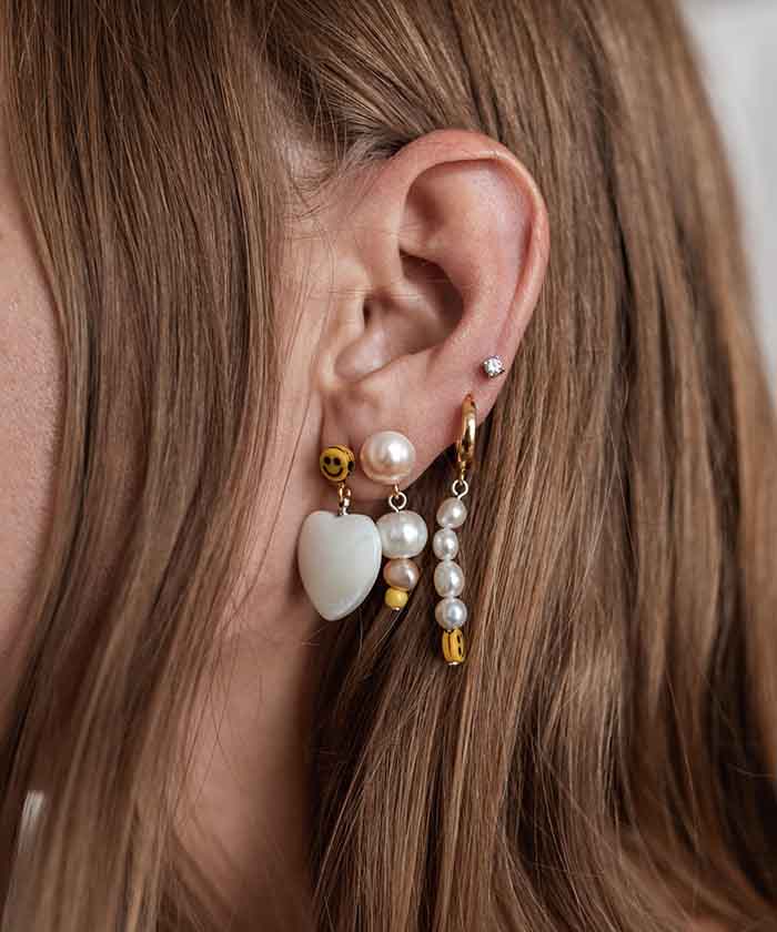 Complete an ear party with the Smilie Dude Earring set featuring gold-plated silver hoops, sweet water pearls, glass pearls, and a smiley