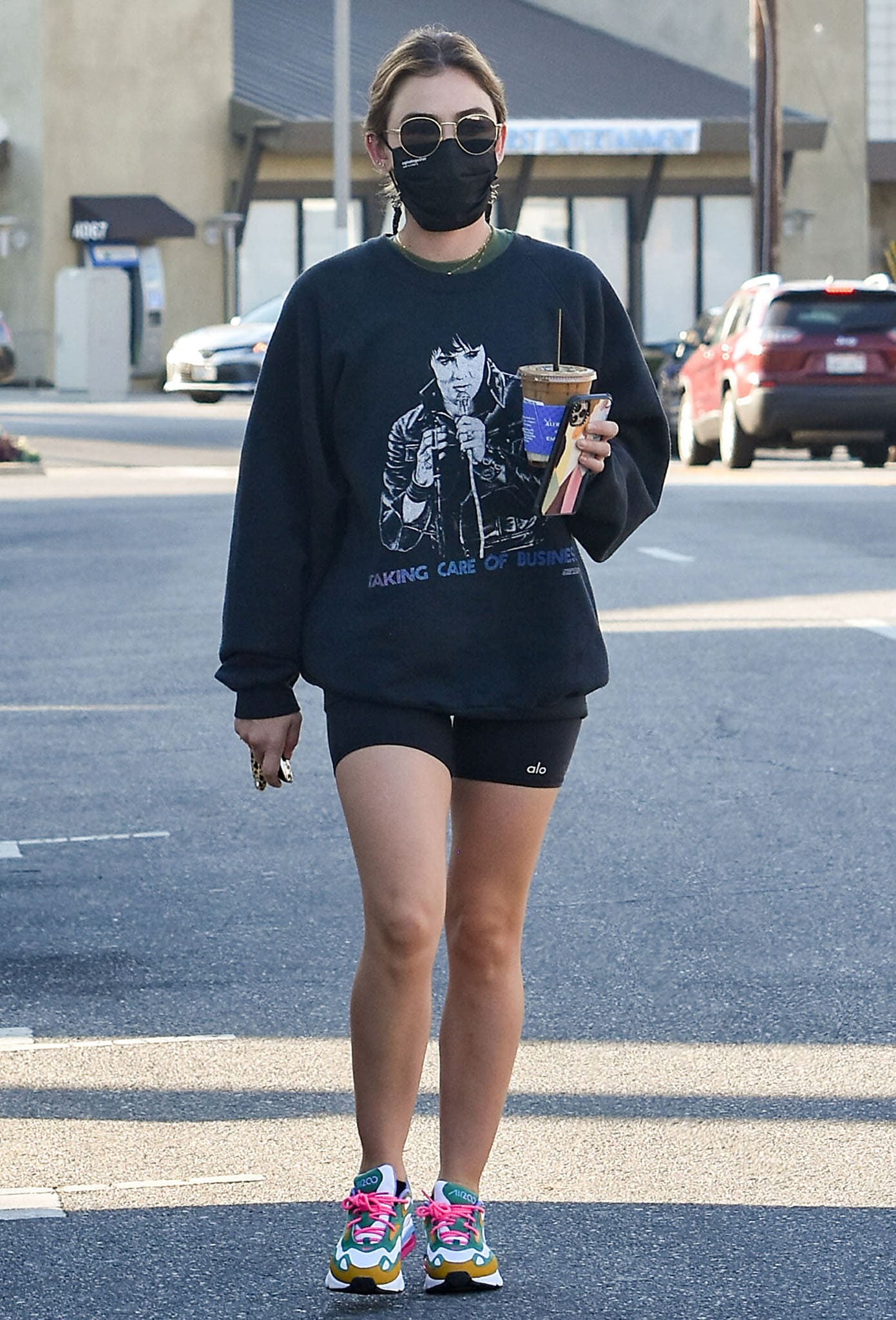 Lucy Hale steps out for coffee after a workout session, sporting a graphic sweatshirt, Alo Yoga high-waist biker shorts, and vibrant Nike Air Max 200 sneakers on February 24, 2021