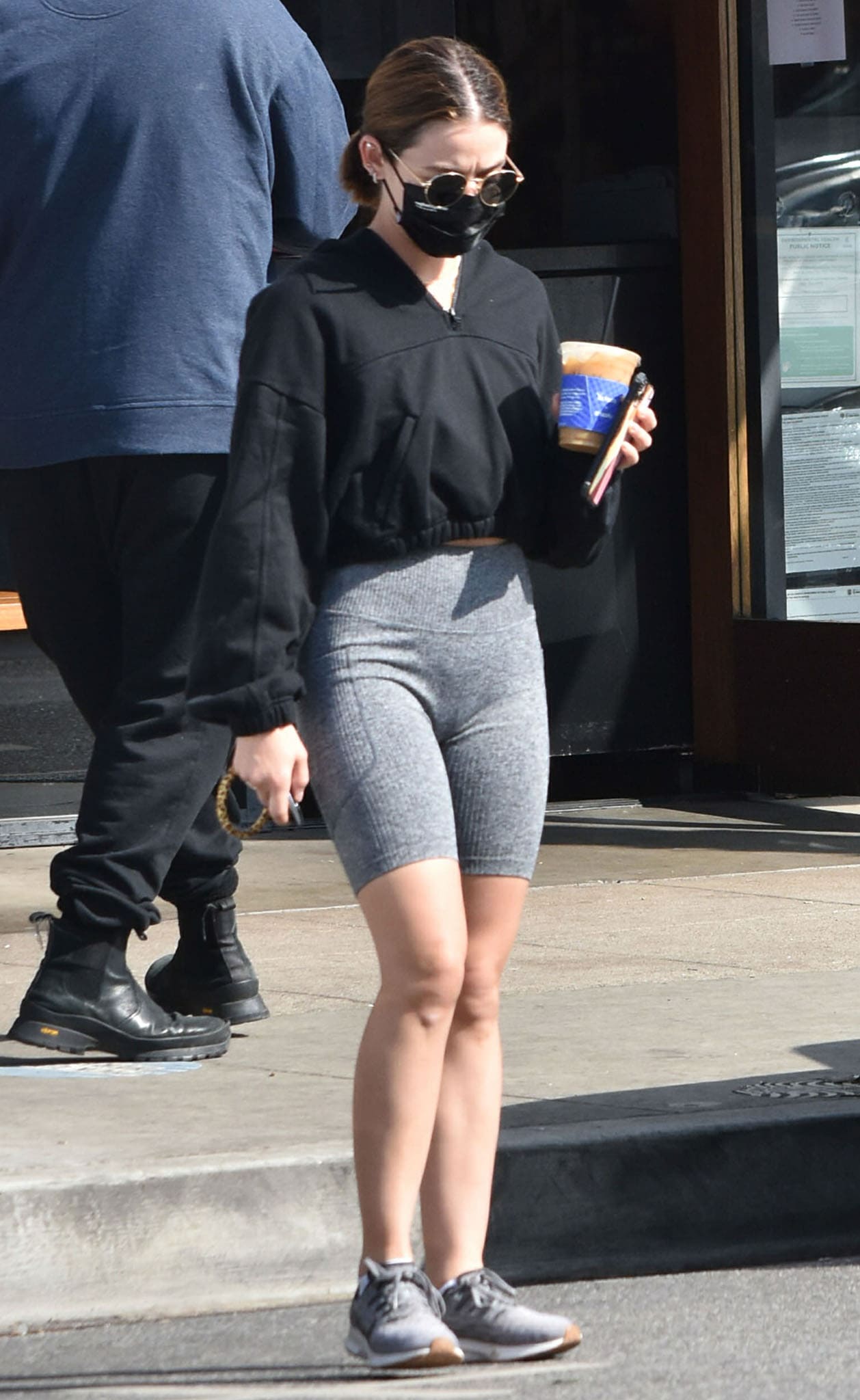 Lucy Hale grabs an iced drink before hiking in Alo Yoga cropped hoodie and Mono B Athleisure shorts on February 8, 2021