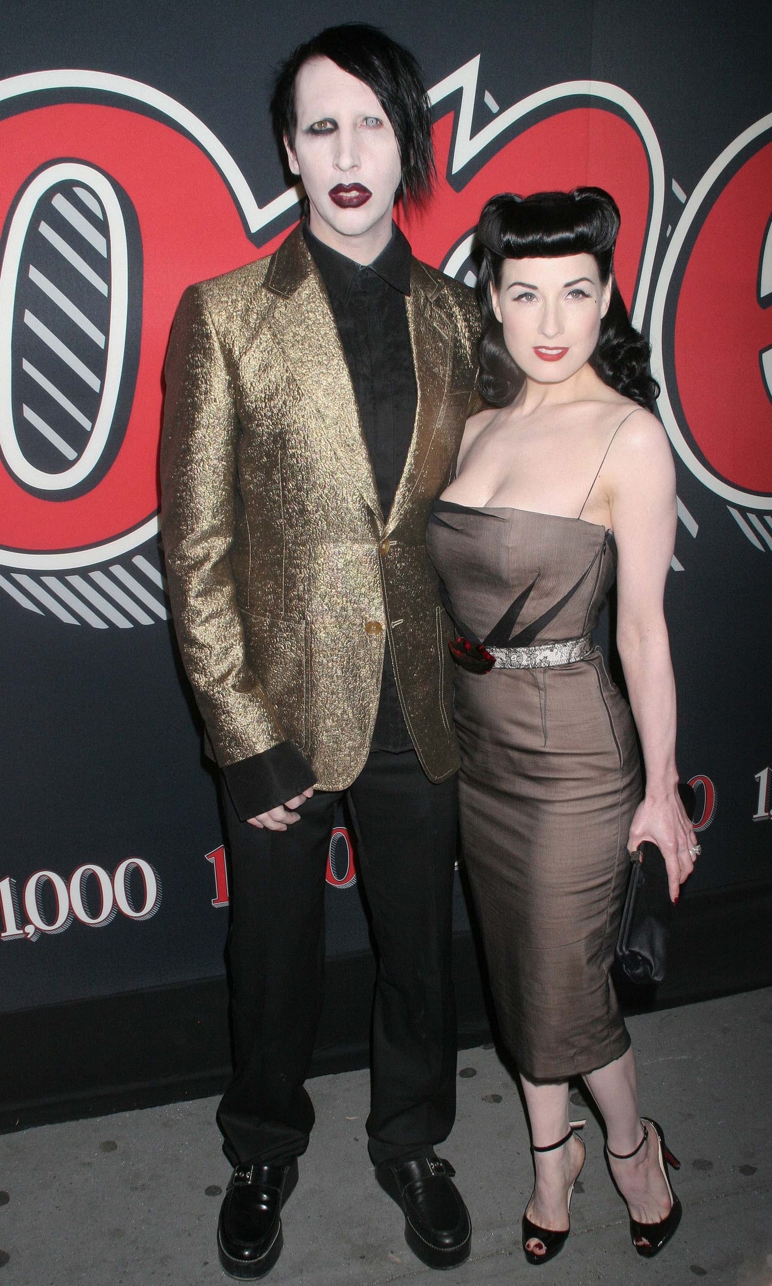 Marilyn Manson and Dita Von Teese bring dramatic flair to the red carpet, with Manson in a striking gold blazer and chunky loafers, while Dita stuns in a sculpted taupe cocktail dress paired with black satin peep-toe heels and her signature retro waves