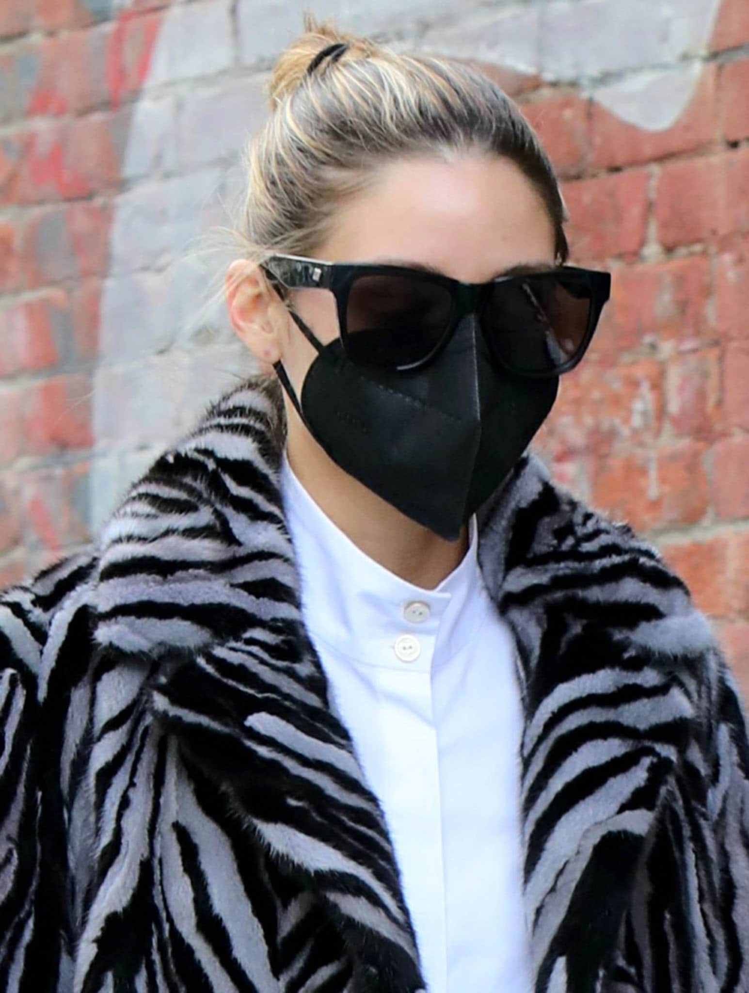 Olivia Palermo keeps things low-key with a casual bun, oversized sunglasses, and a black face mask