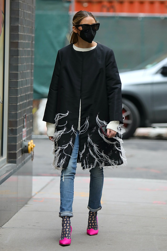 Olivia Palermo layers a feathered coat dress over a sweater and a pair of jeans