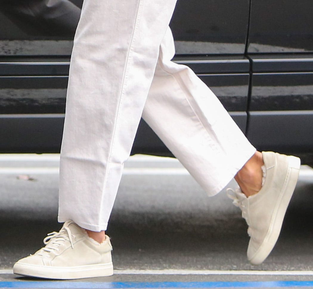 Alessandra Ambrosio completes her off-duty look with light gray suede Common Projects sneakers, featuring cozy shearling lining and the brand’s signature gold-stamped heel detail