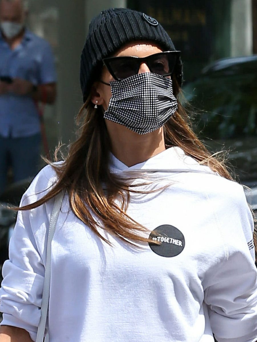 Alessandra Ambrosio styles her sporty look with a Ruslan Baginskiy beanie, a plaid face mask, and black cat eye sunglasses