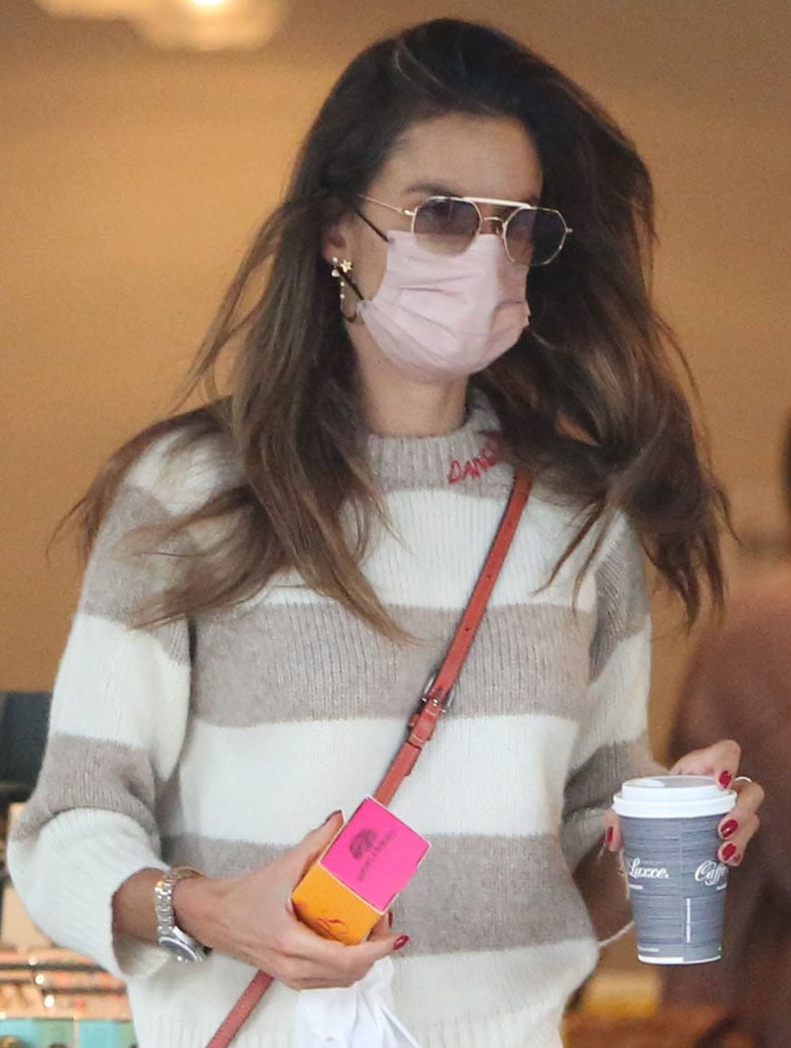 Alessandra Ambrosio wears her long wavy tresses down and styles her look with sunglasses, pink face mask, and gold earrings