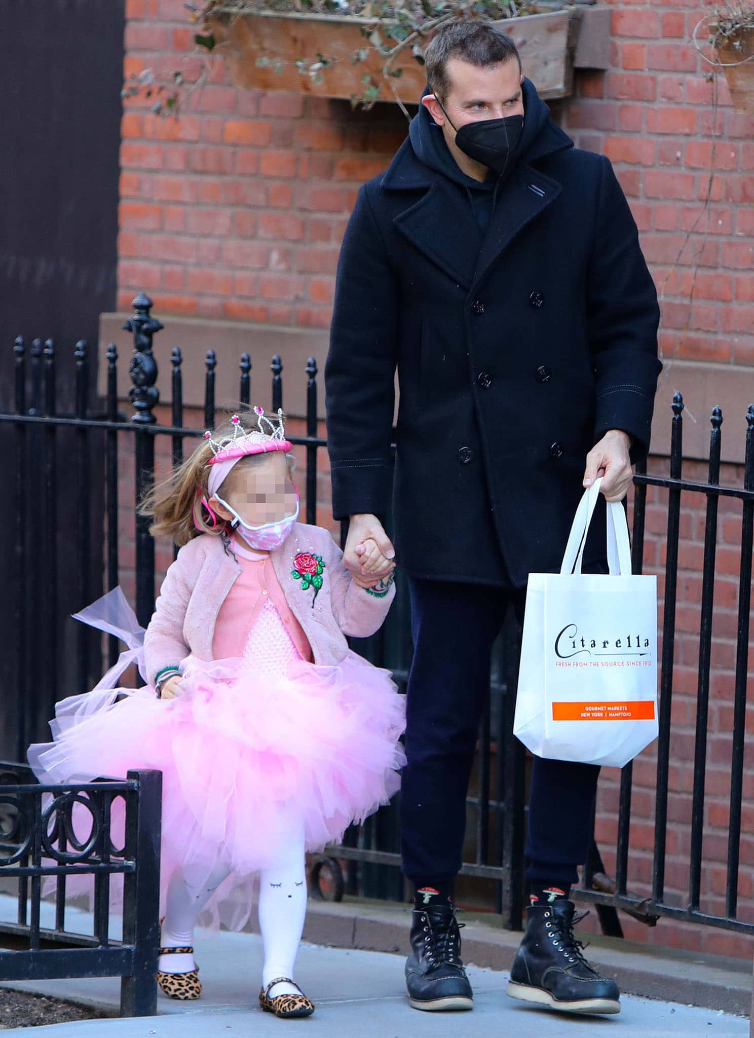 Bradley Cooper wears a black pea coat as he holds hands with his daughter