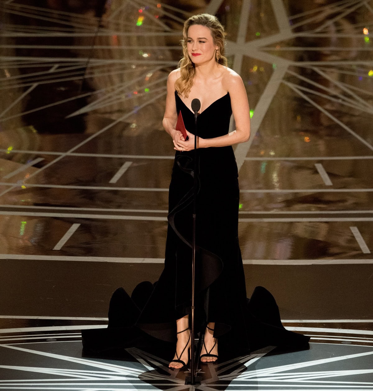 Brie Larson steps onto the Academy Awards stage on February 26, 2017, in a custom black Oscar de la Renta gown paired with sleek black suede Aquazzura “Casanova” sandals that added a refined, minimalist finish to her dramatic look