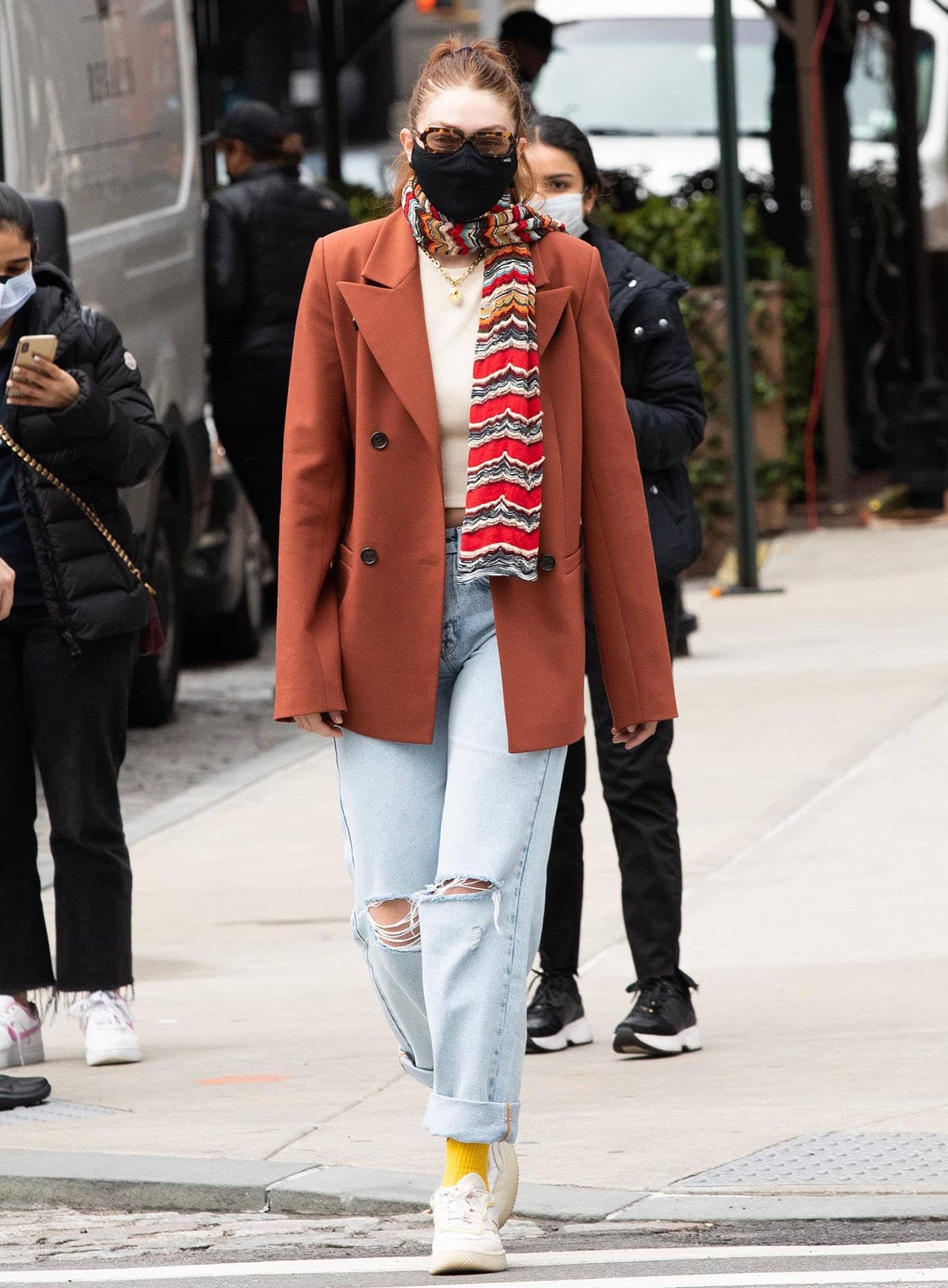 Gigi Hadid adds more color to her chic look with a striped scarf and a pair of Petals and Peacocks yellow socks