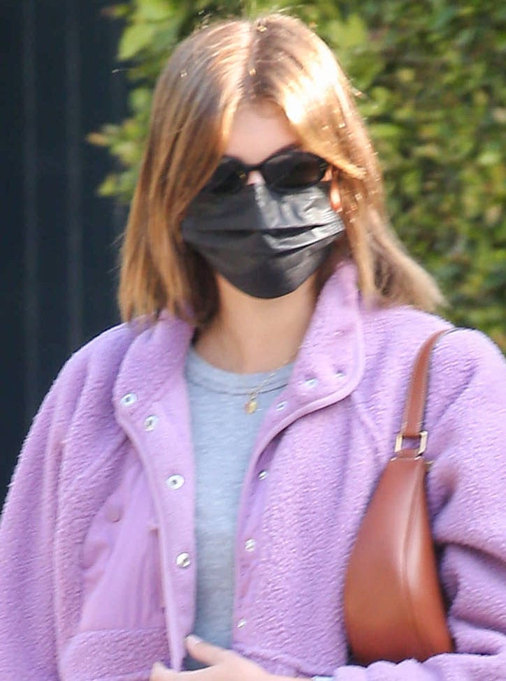 Kaia Gerber covers her face with a black face mask and a pair of Kate Young for Tura sunnies