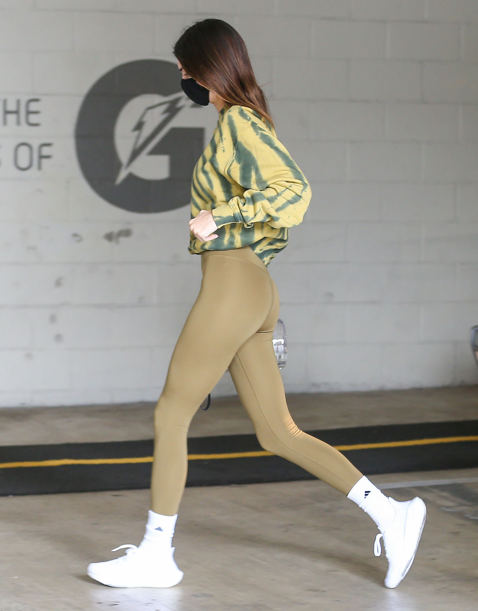 Kendall Jenner wears olive green Alo leggings and a Good American tie-dye sweatshirt to the gym