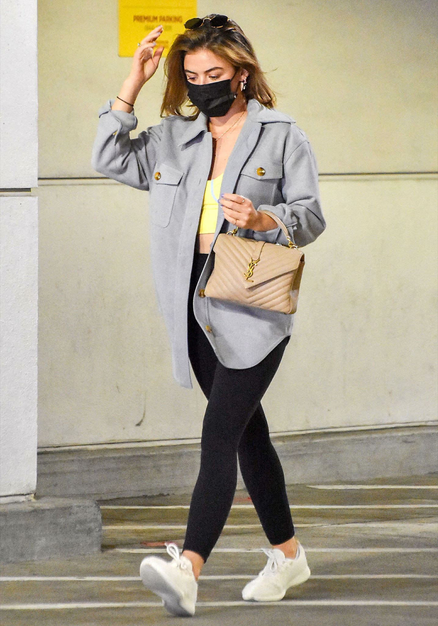 Lucy Hale exudes effortless athleisure chic in a yellow Fabletics x Madelaine Petsch sports bra, black leggings, a gray Good American shacket, and Allbirds sneakers while shopping at Target on March 9, 2021