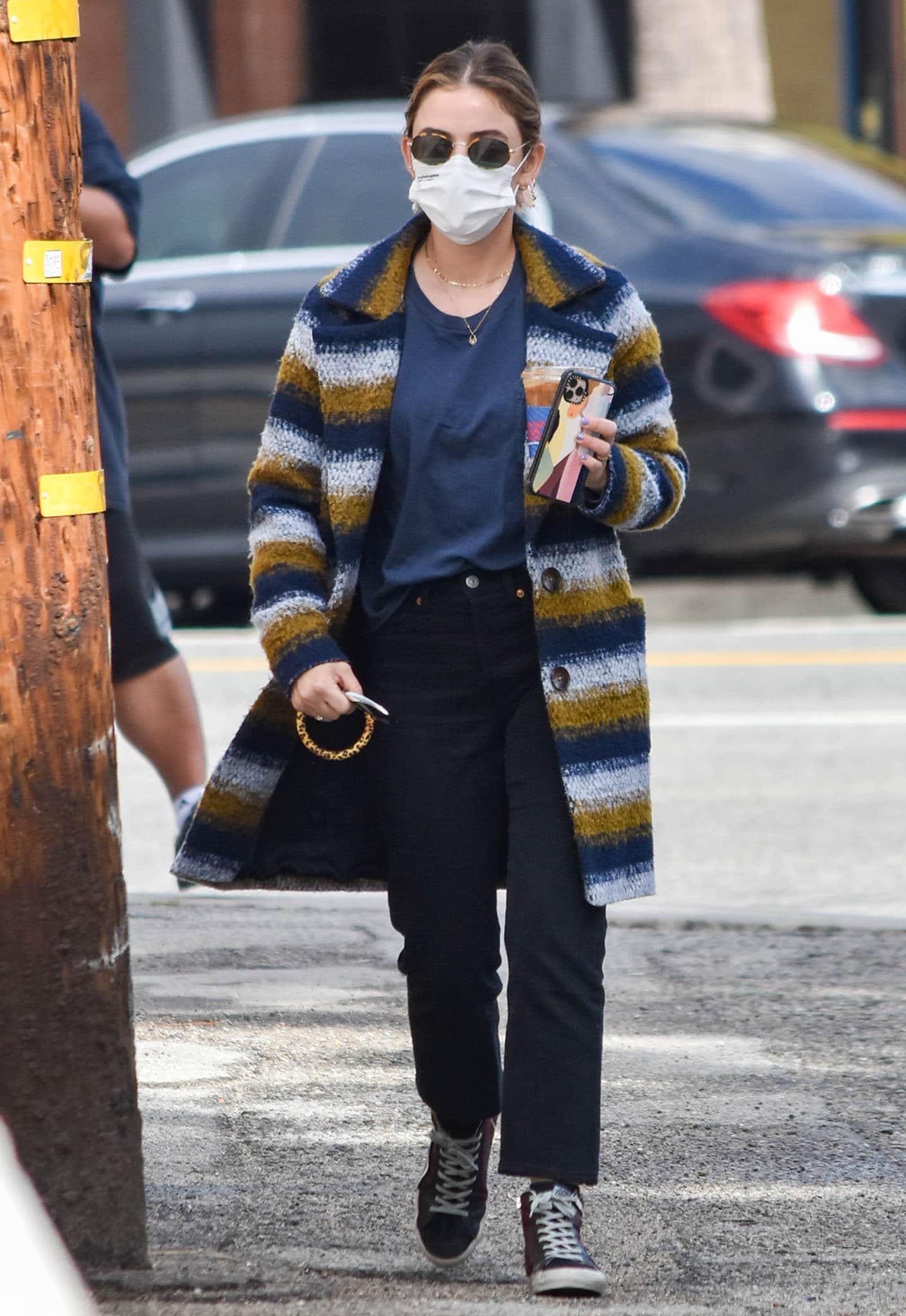 Lucy Hale keeps it effortlessly chic in a multicolored striped coat, navy tee, black jeans, and Golden Goose sneakers while grabbing iced coffee in Los Angeles on March 11, 2021
