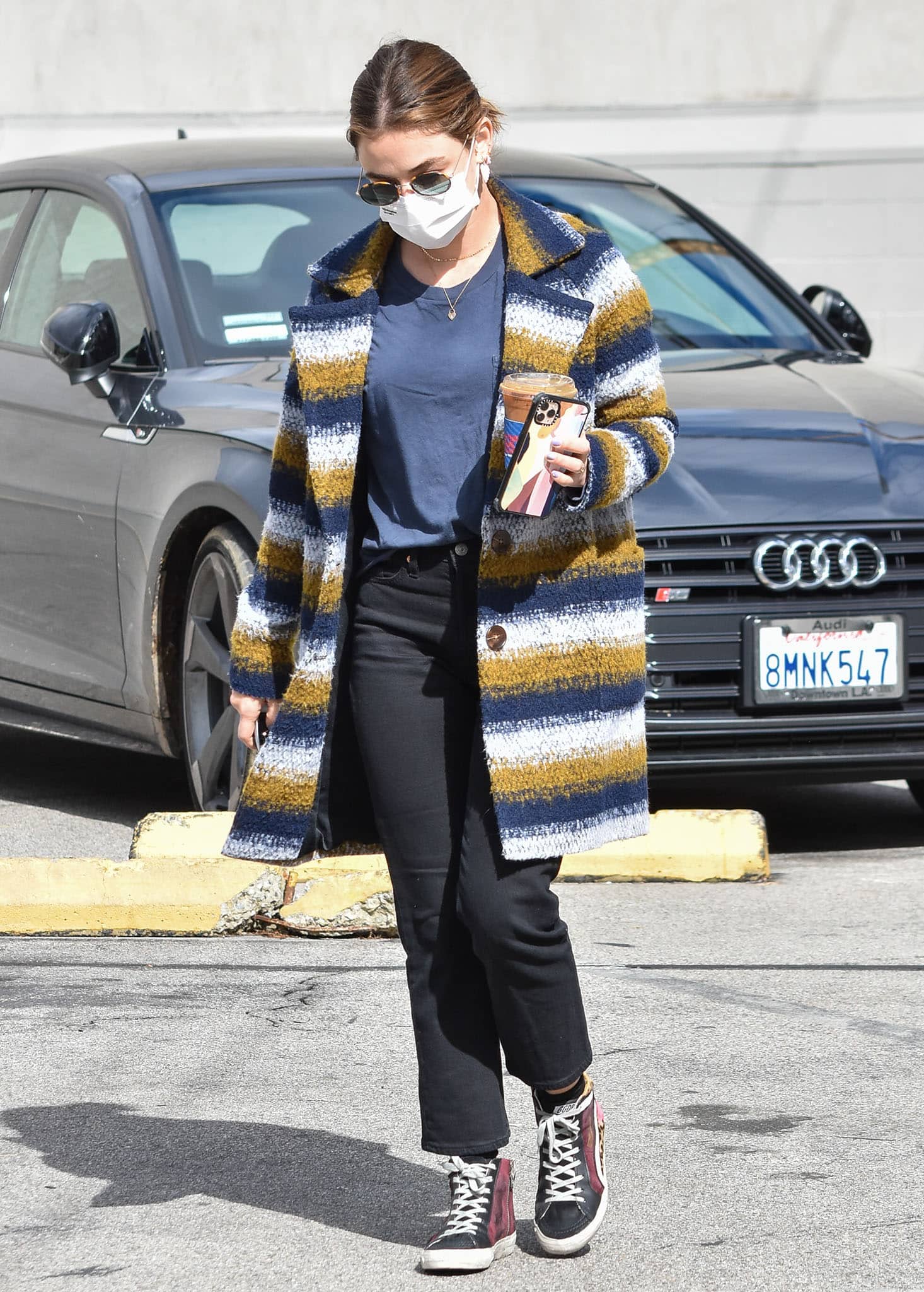 Lucy Hale wears a chic multicolored striped coat with a navy tee and black jeans