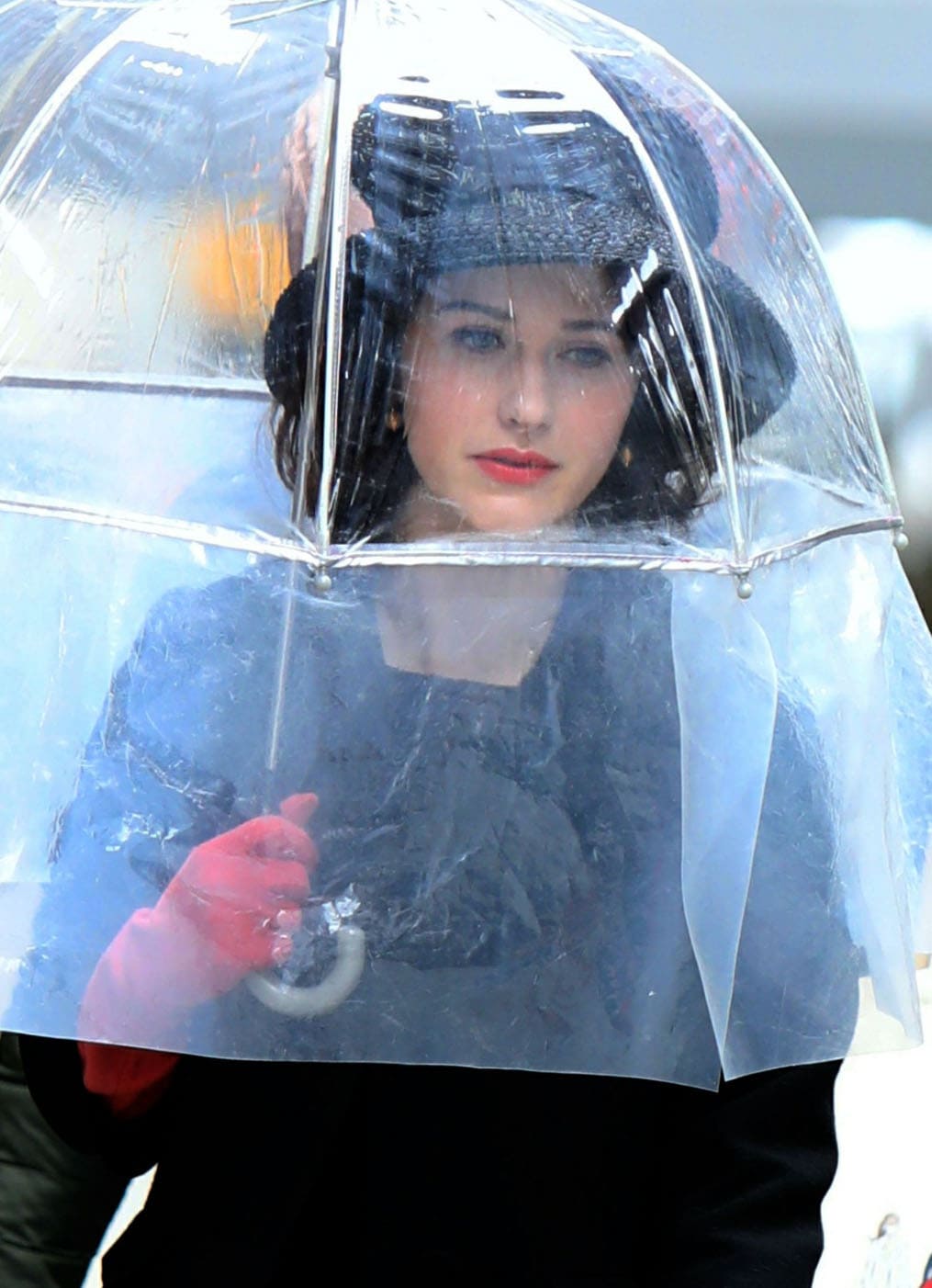 Rachel Brosnahan teams her black coat with a black hat and pink opera gloves