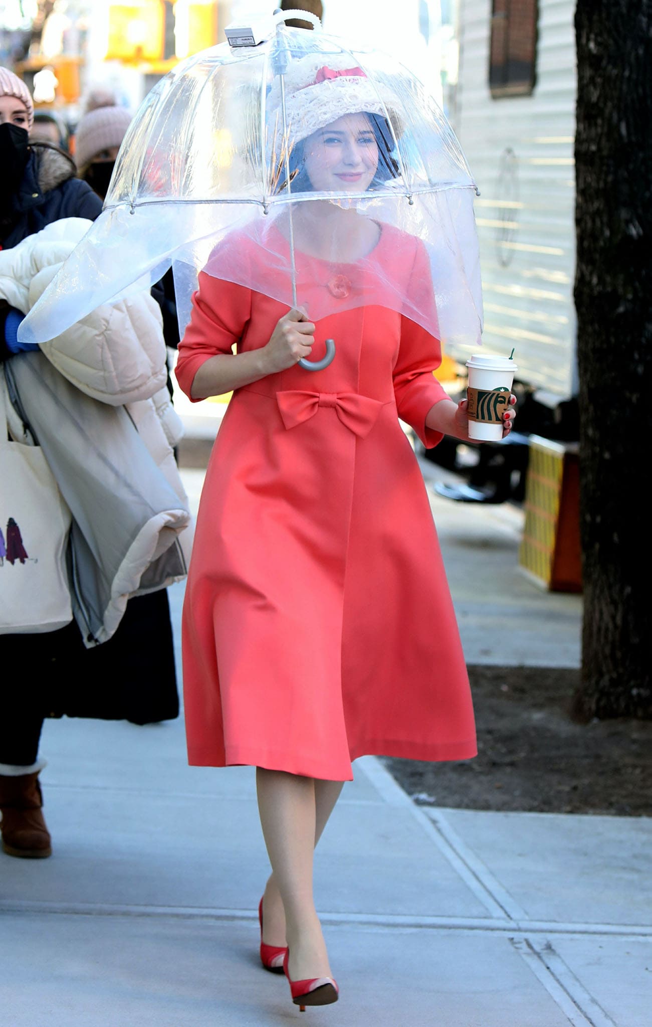Rachel Brosnahan wearing a vintage pink coat dress with a lace hat on The Marvelous Mrs. Maisel set on March 2, 2021