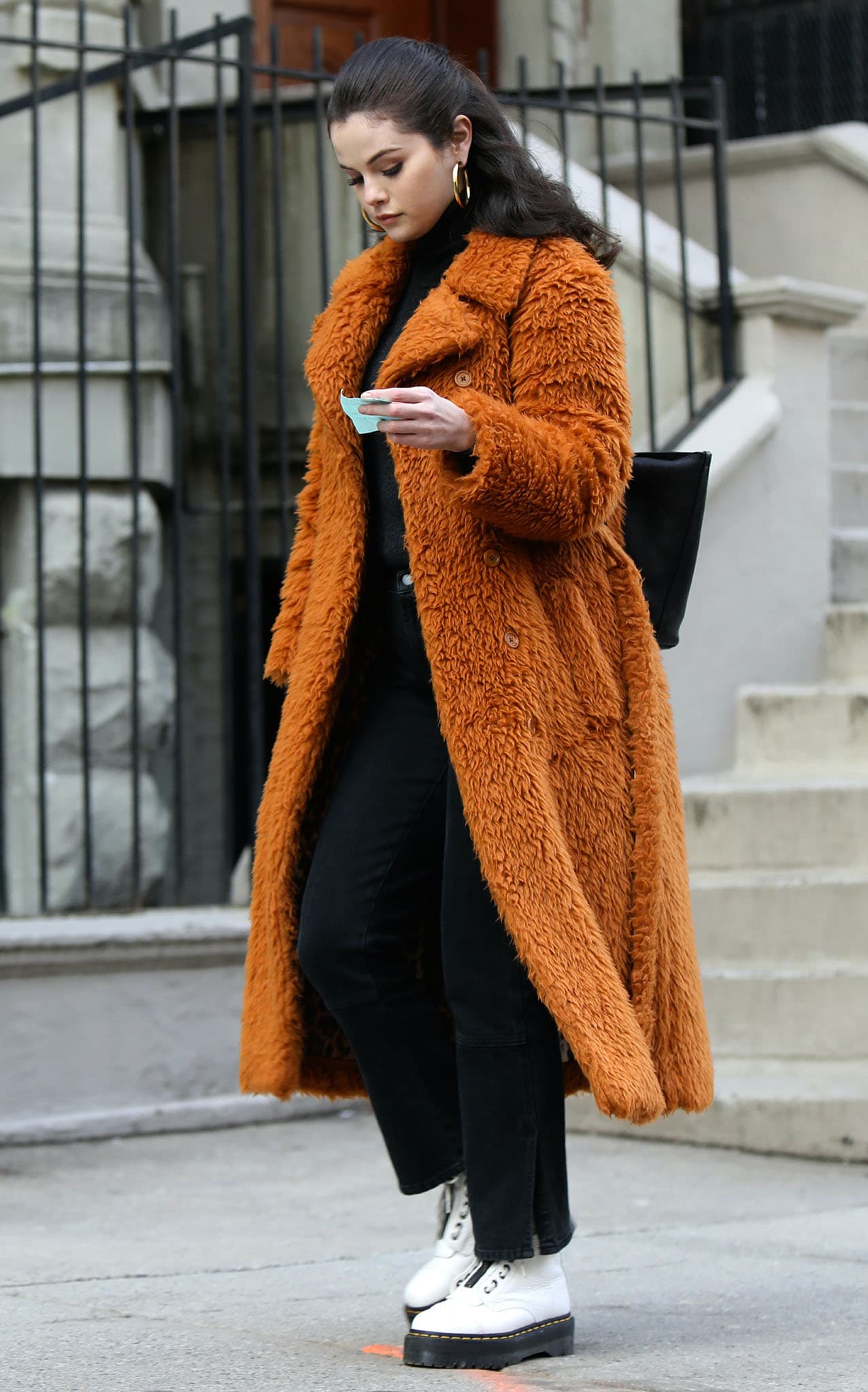 Selena Gomez wearing a brown teddy faux fur coat with a black turtleneck sweater