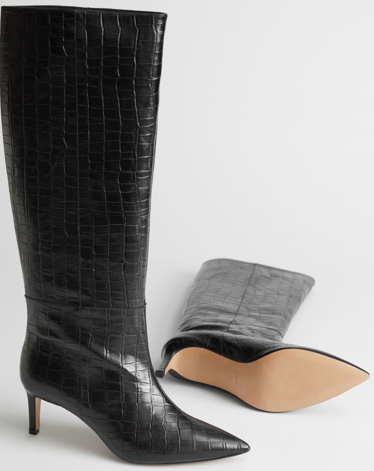 Step into the '90s revival with & Other Stories' croc-embossed leather knee-high boots, featuring sleek stiletto heels and a chic pointed silhouette, perfect for any contemporary wardrobe