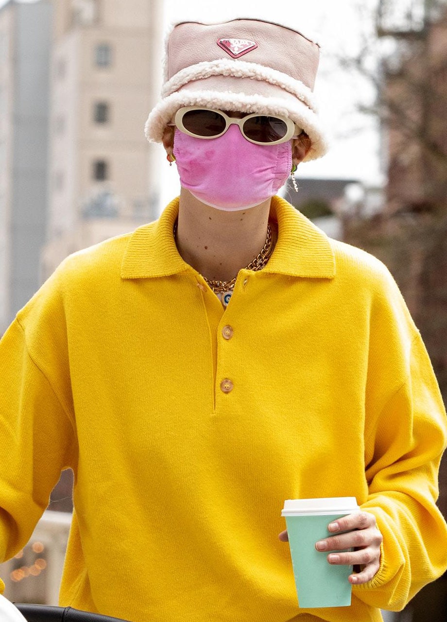 Gigi Hadid teams her yellow tracksuit with a cozy Prada fur-lined bucket hat and a pink face mask