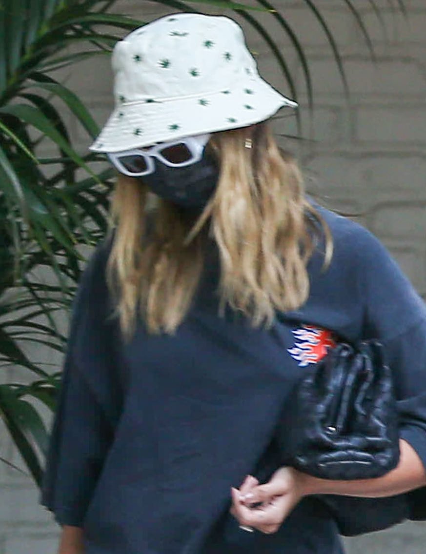 Hailey Bieber keeps a low profile with Urban Outfitters bucket hat, Oscar and Frank sunglasses, and a black face mask