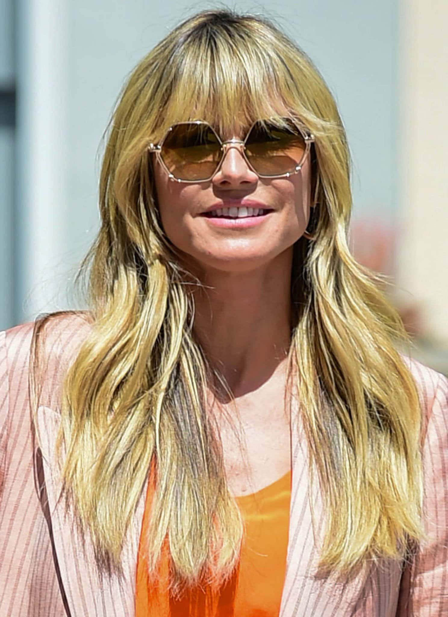 Heidi Klum styles her fringe hair in loose waves and wears a pair of hexagonal sunglasses