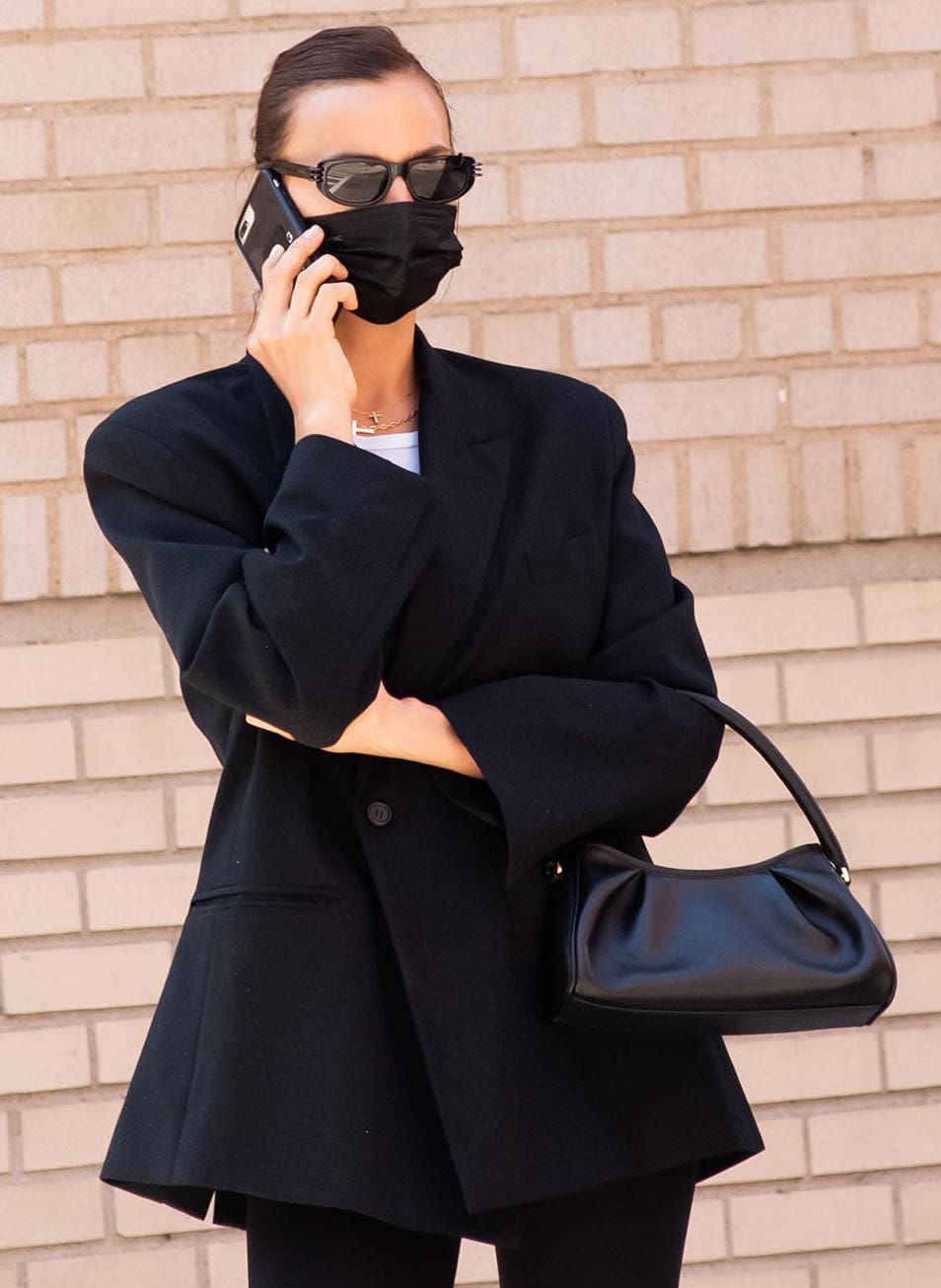 Irina Shayk wears her hair up in a bun and covers her face with black face mask and Givenchy's Pierced Amina sunglasses