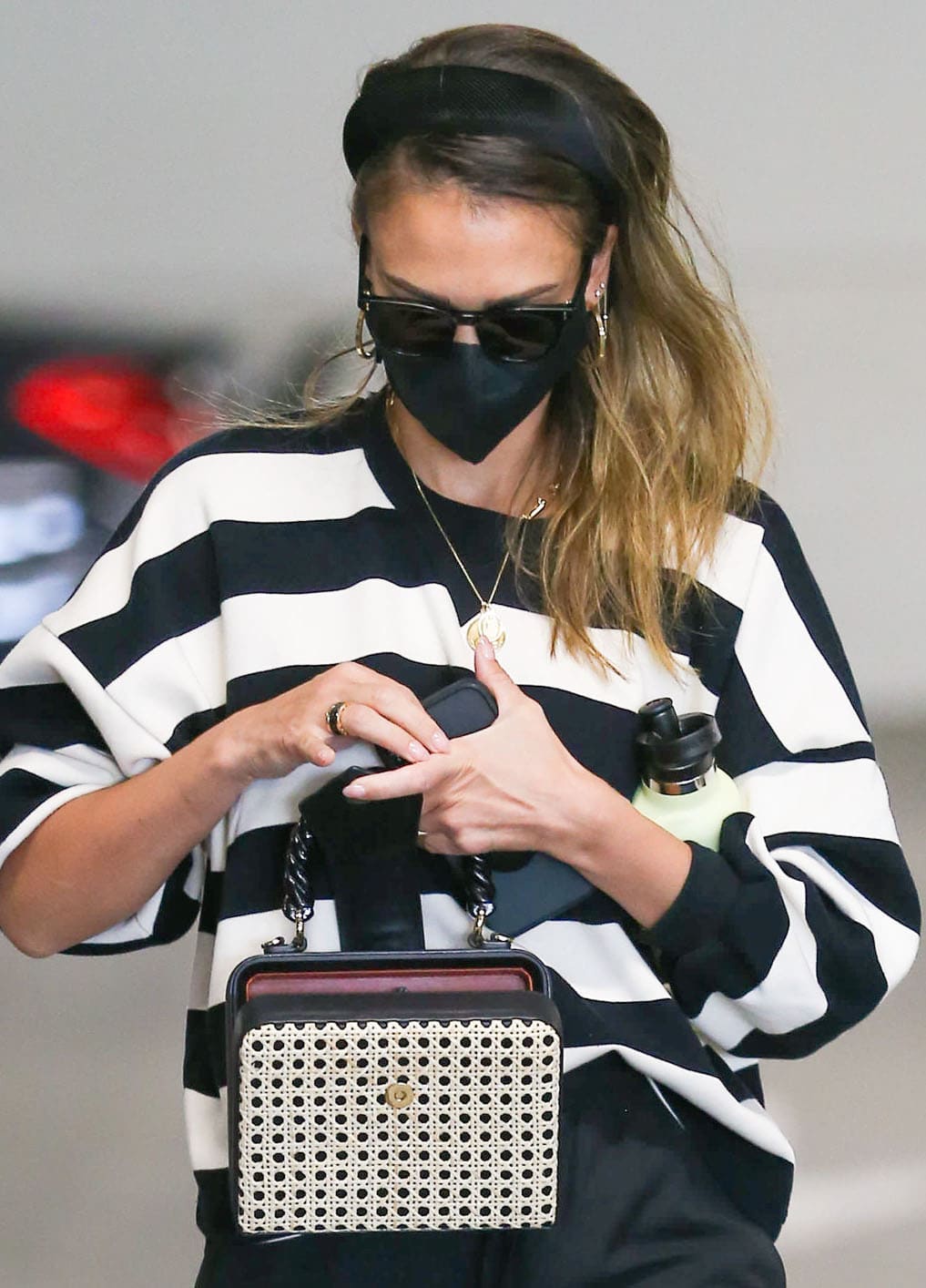 Jessica Alba elevates her casual look with gold jewelry and wears her hair down with a black headband 