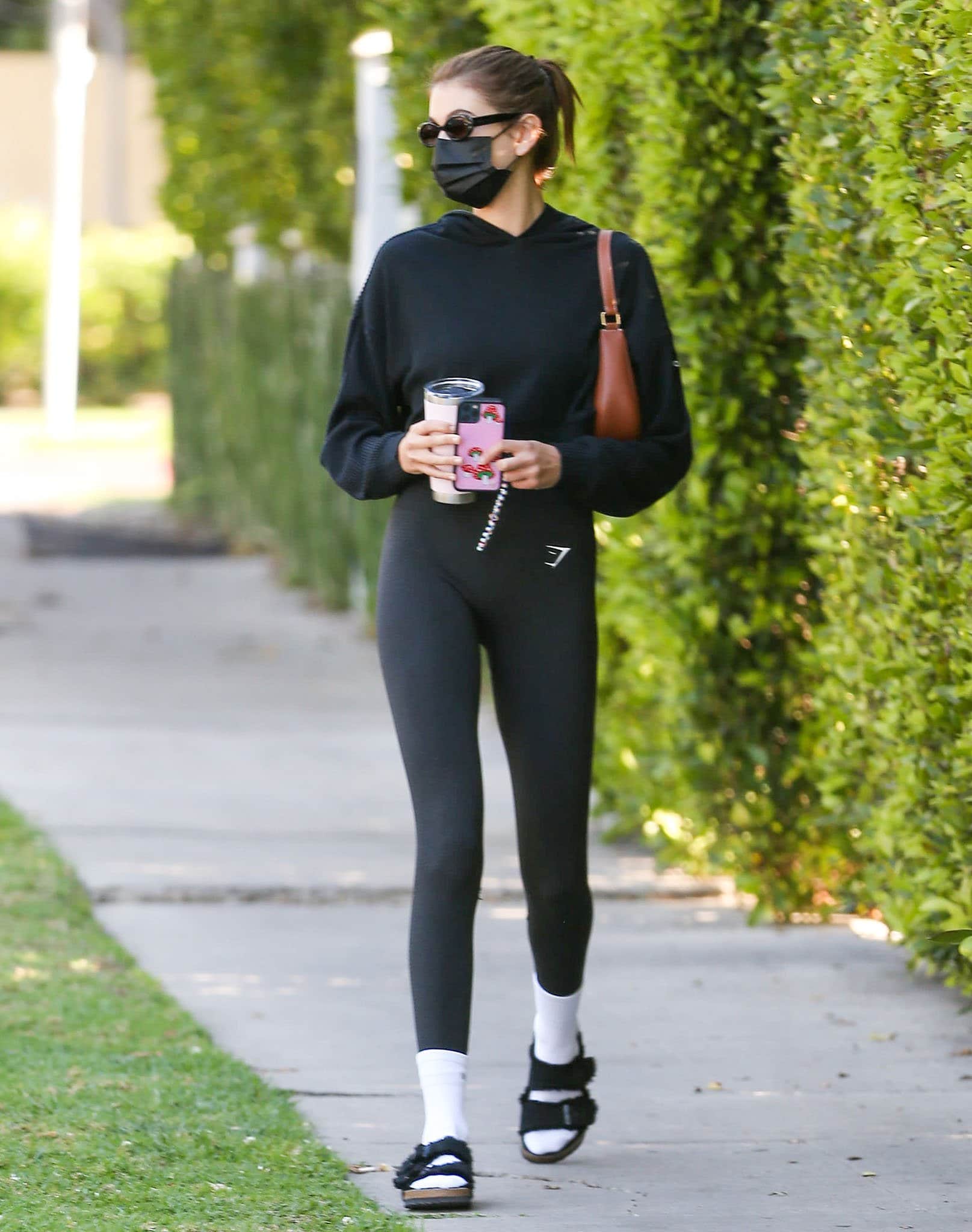 Kaia Gerber wears her furry Birks with Active Set white socks, Gymshark leggings, and Alo Yoga hoodie on April 1, 2021