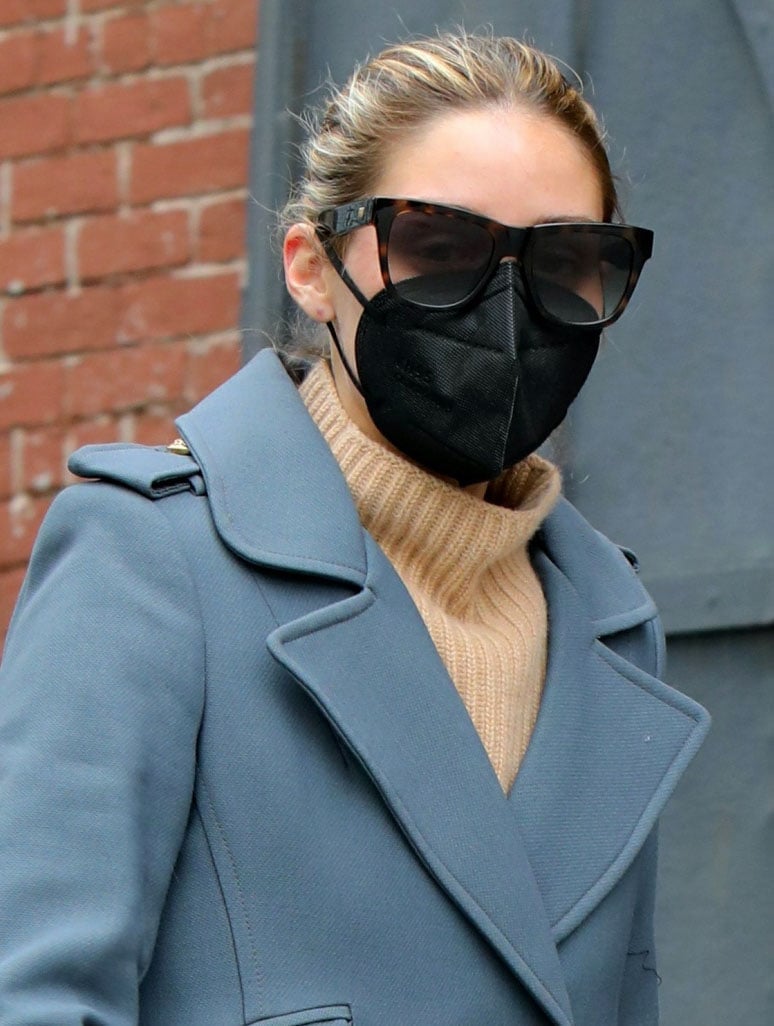 Olivia Palermo ties her hair in a bun and covers her face with tortoiseshell sunglasses and a black face mask