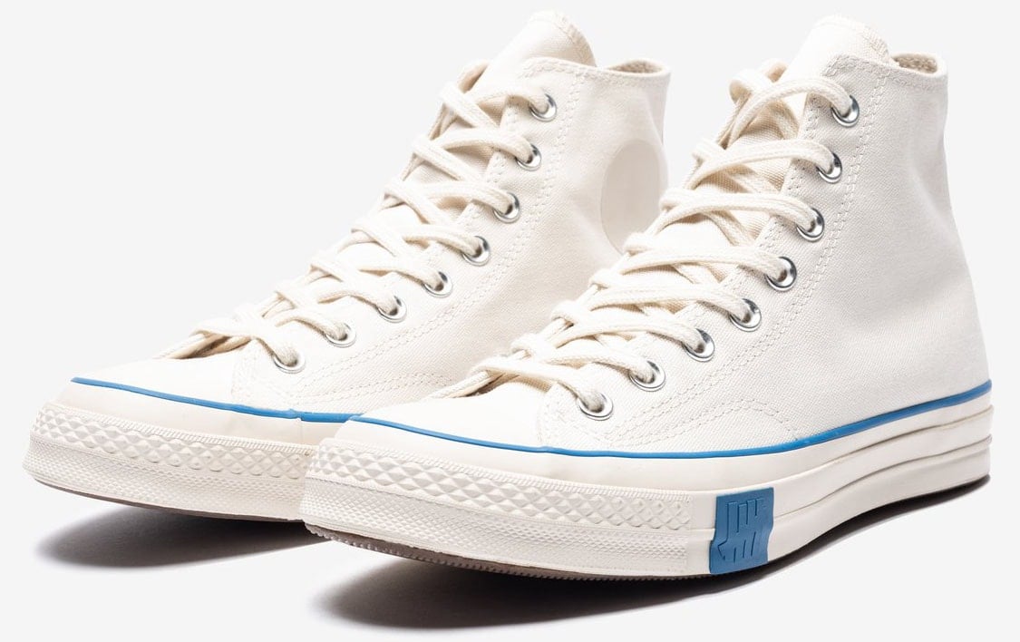 A minimalist pair of Converse Chucks with blue trims and Undefeated branding