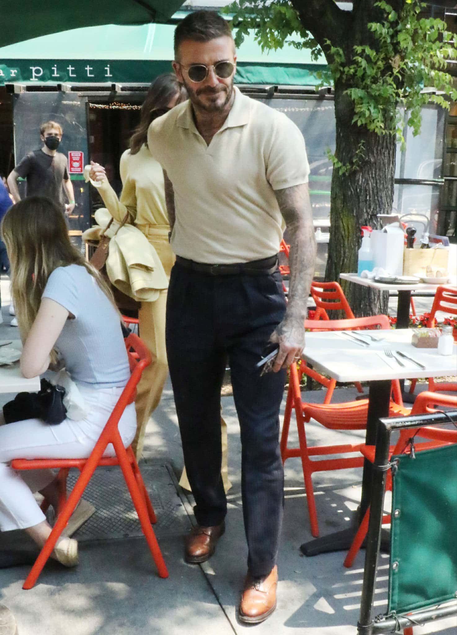 David Beckham color-coordinates with his wife in a pastel yellow polo shirt with pinstripe pants and brown shoes